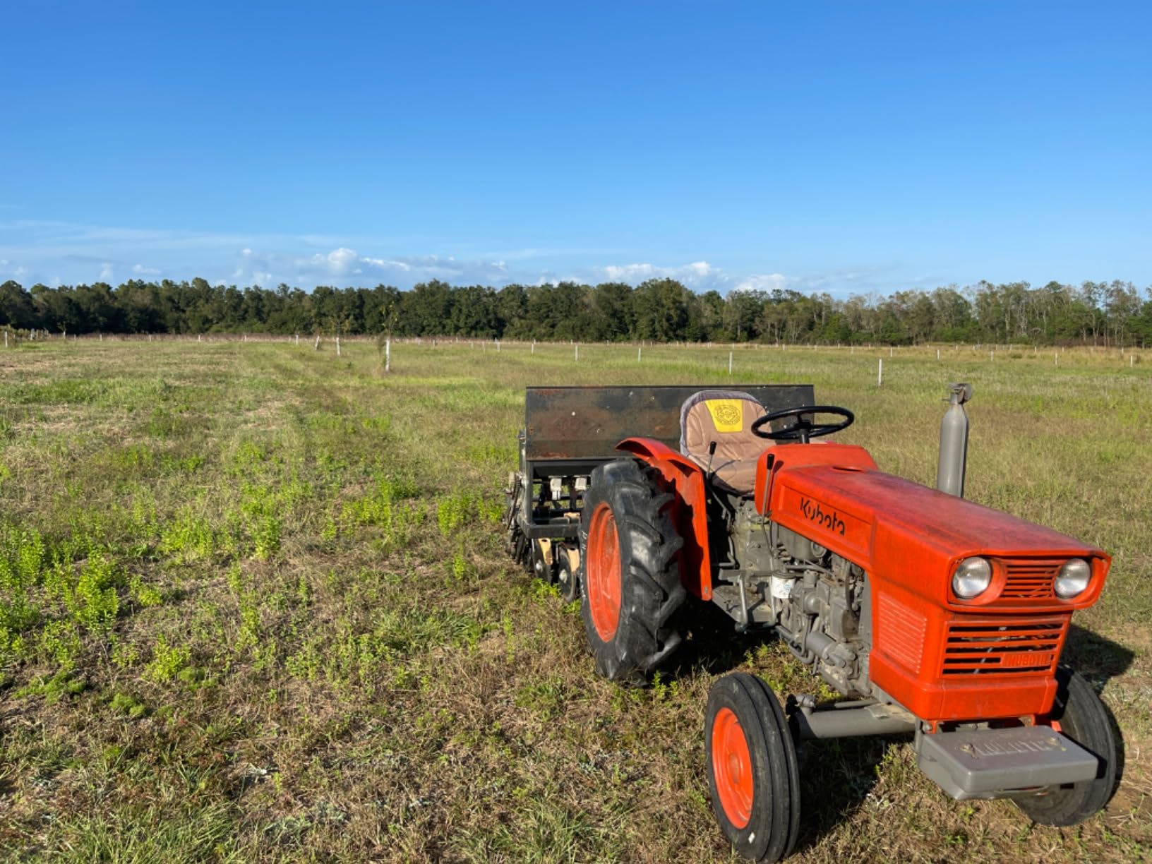 Field Tuff 3-point seeder mounted on a Kubota compact tractor in a fenced pasture