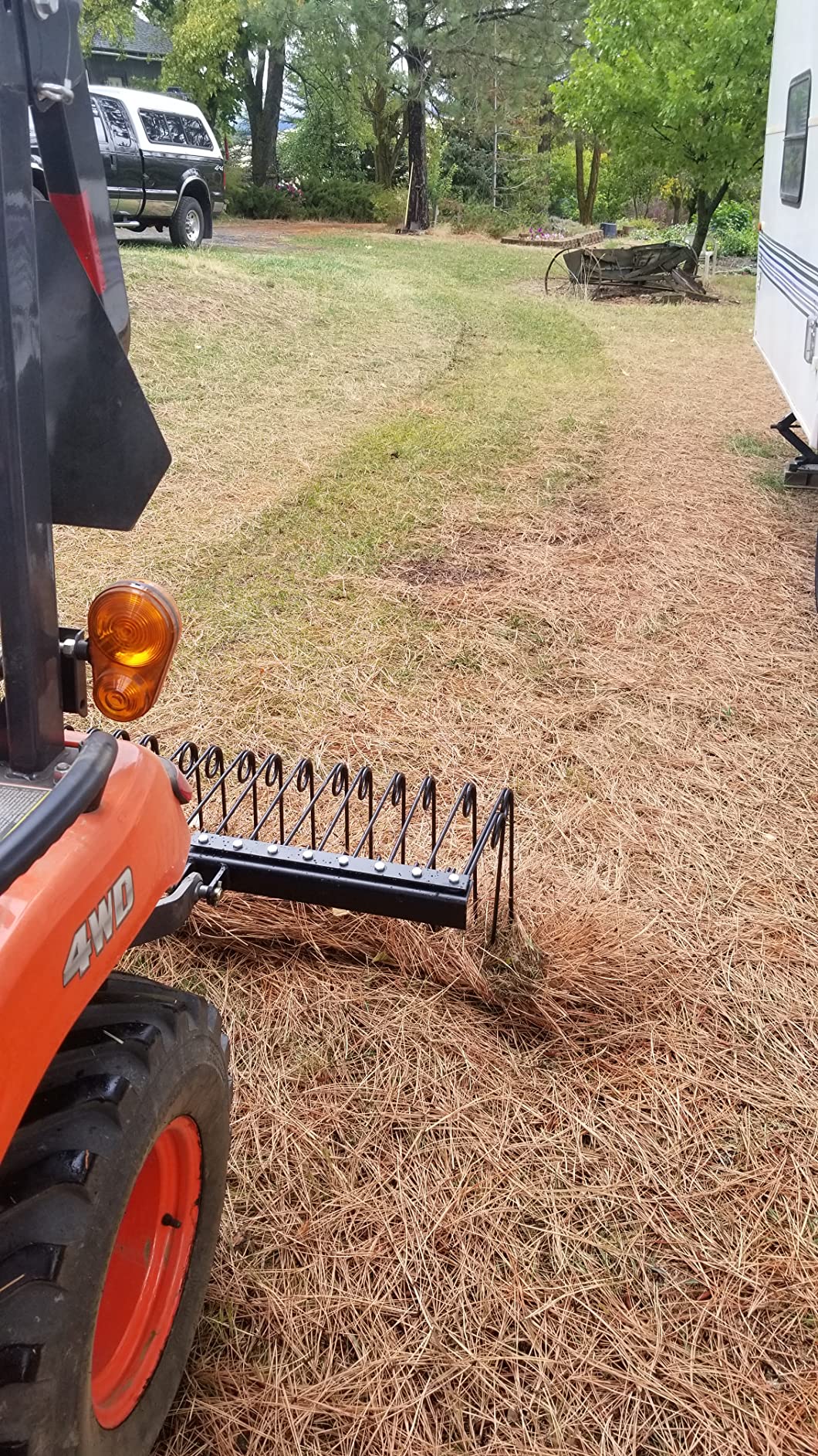 Field Tuff spring tine rake on a tractor 3-point hitch pulling pine needles across a yard